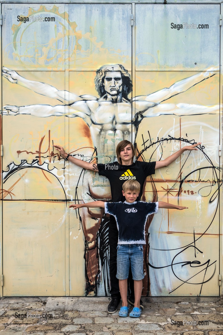 ENFANTS LES BRAS EN CROIX DEVANT UNE REPRODUCTION DE L'HOMME DE VITRUVE, DESSIN ANATOMIQUE DE LEONARD DE VINCI, ROCHEFORT, CHARENTE-MARITIME (17), FRANCE 