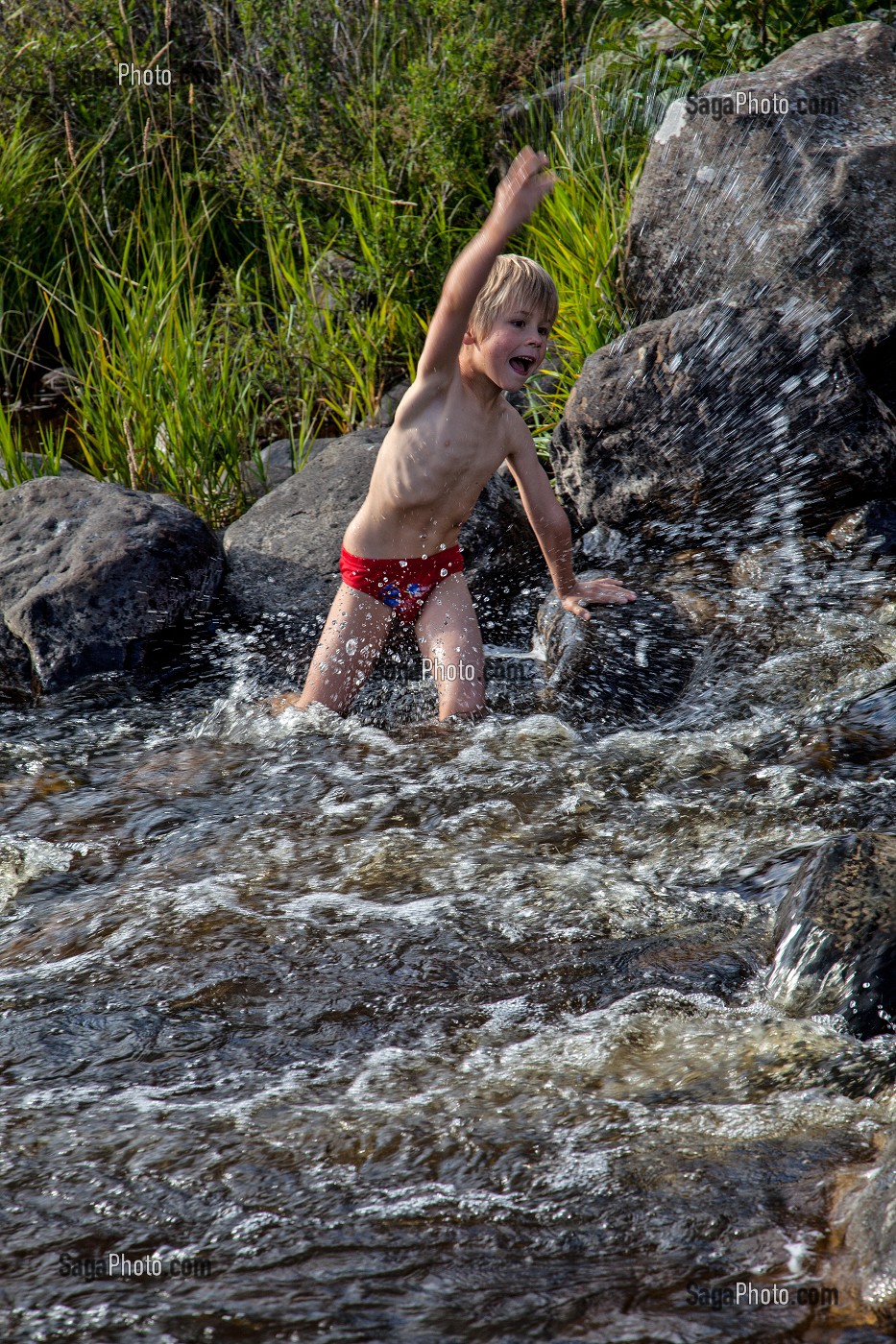ENFANT JOUANT DANS L'EAU D'UNE RIVIERE, NASBINALS, LOZERE (48), AUBRAC, FRANCE 