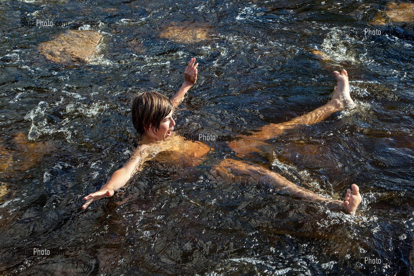 ENFANT JOUANT DANS L'EAU D'UNE RIVIERE, NASBINALS, LOZERE (48), AUBRAC, FRANCE 