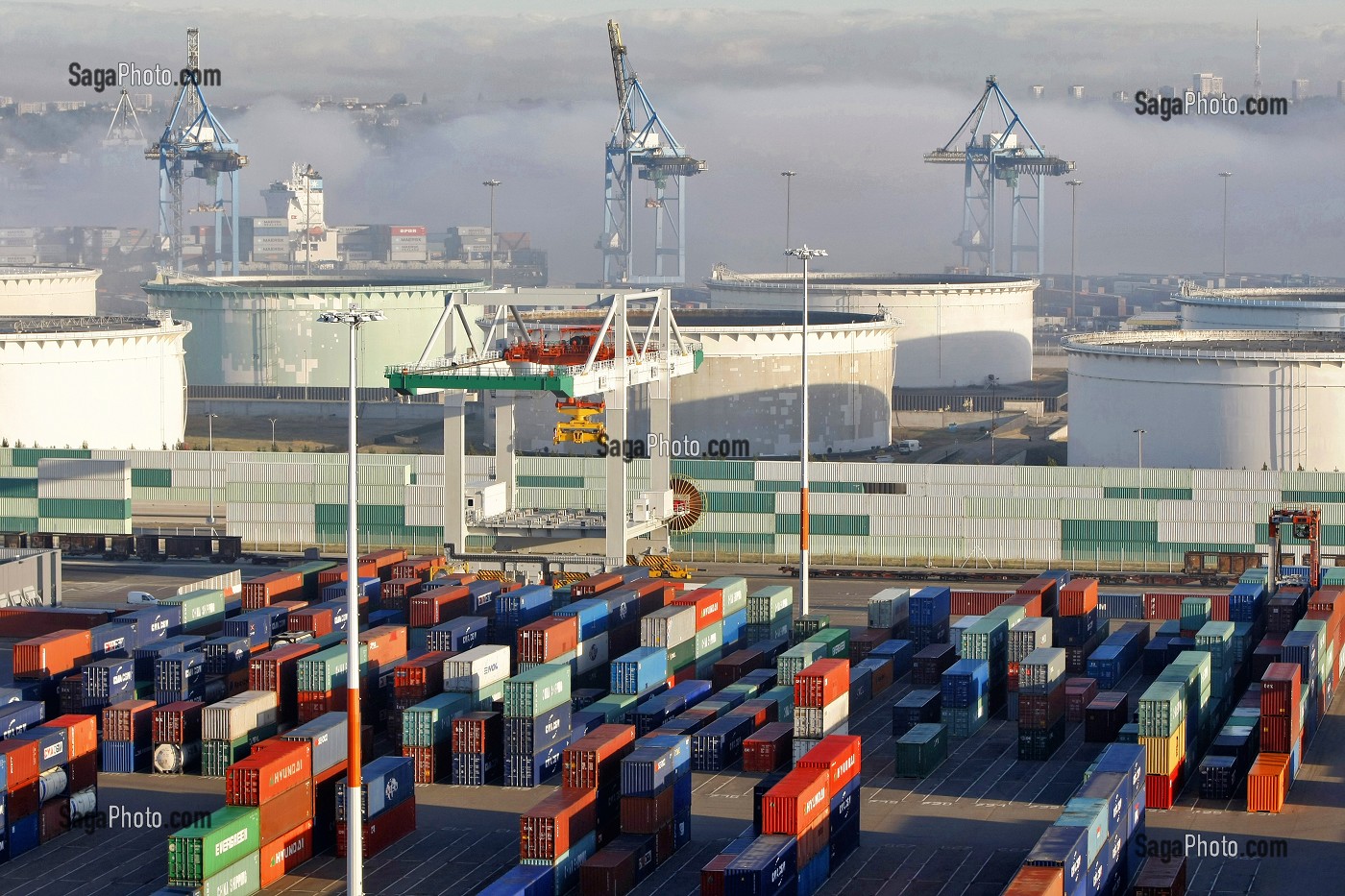 ZONE DE STOCKAGE DES CONTENEURS ET CUVES DE PETROLE SUR LE TERMINAL DE FRANCE, PORT 2000, PORTIQUE DE CHARGEMENT DANS LA BRUME DU MATIN, PORT DE COMMERCE, LE HAVRE, NORMANDIE 