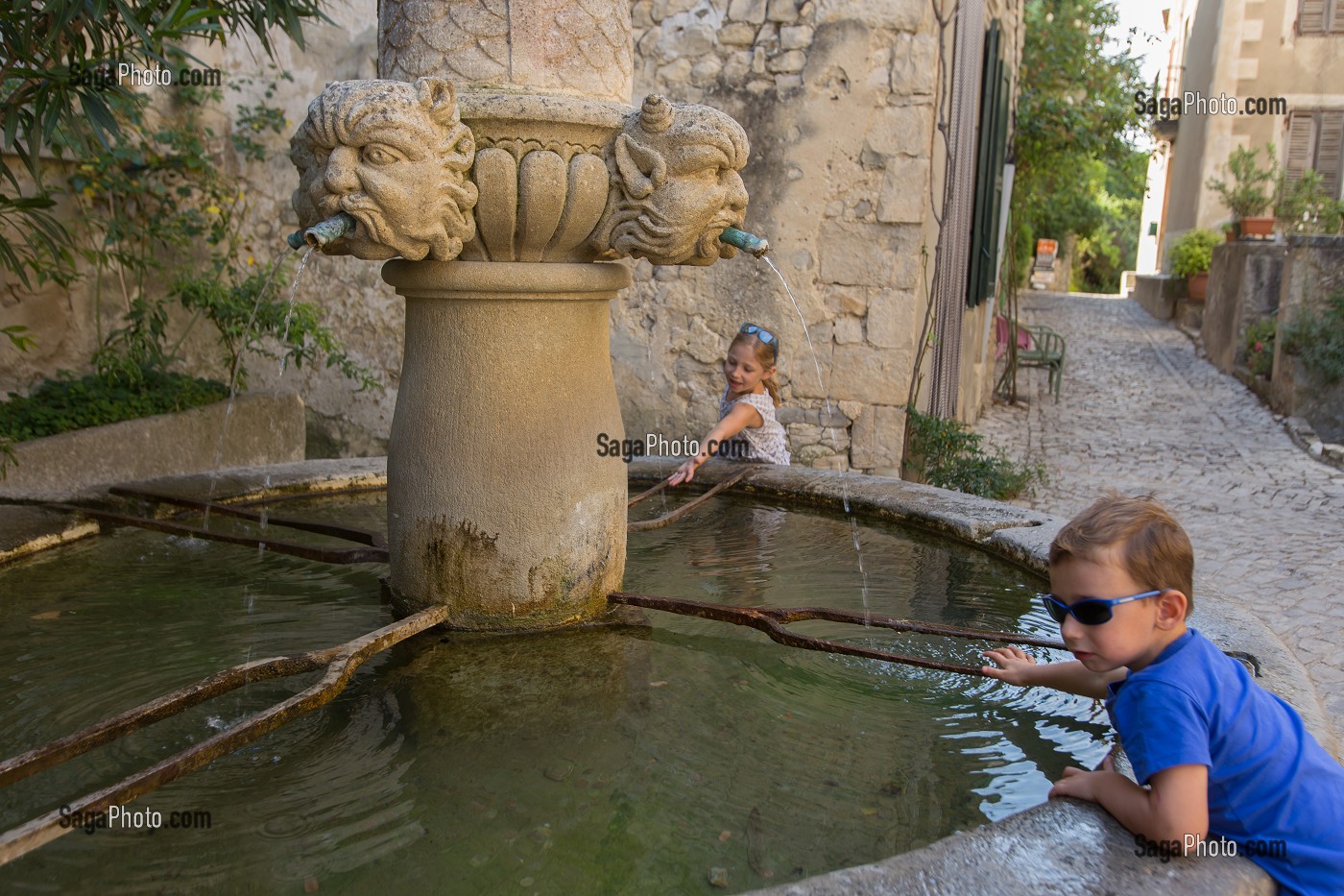 ENFANT JOUANT AU BORD D'UNE FONTAINE A MASCARONS, VILLAGE DE SEGURET, LABELLISE PLUS BEAUX VILLAGE DE FRANCE, VAUCLUSE (84), FRANCE 