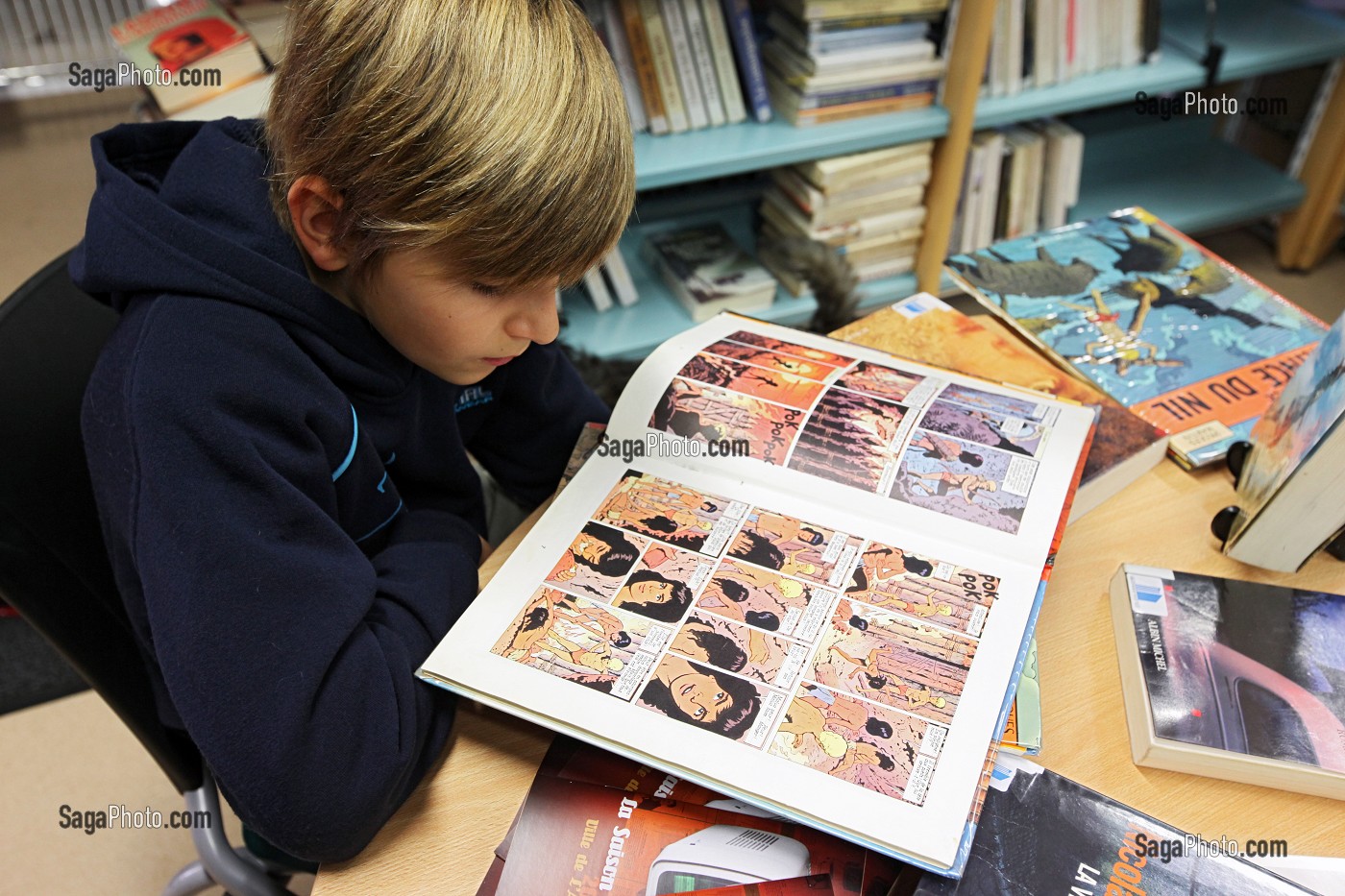 ENFANT LISANT UNE BANDE DESSINEE DANS UNE BIBLIOTHEQUE, RUGLES, EURE (27), HAUTE-NORMANDIE, FRANCE, EUROPE 