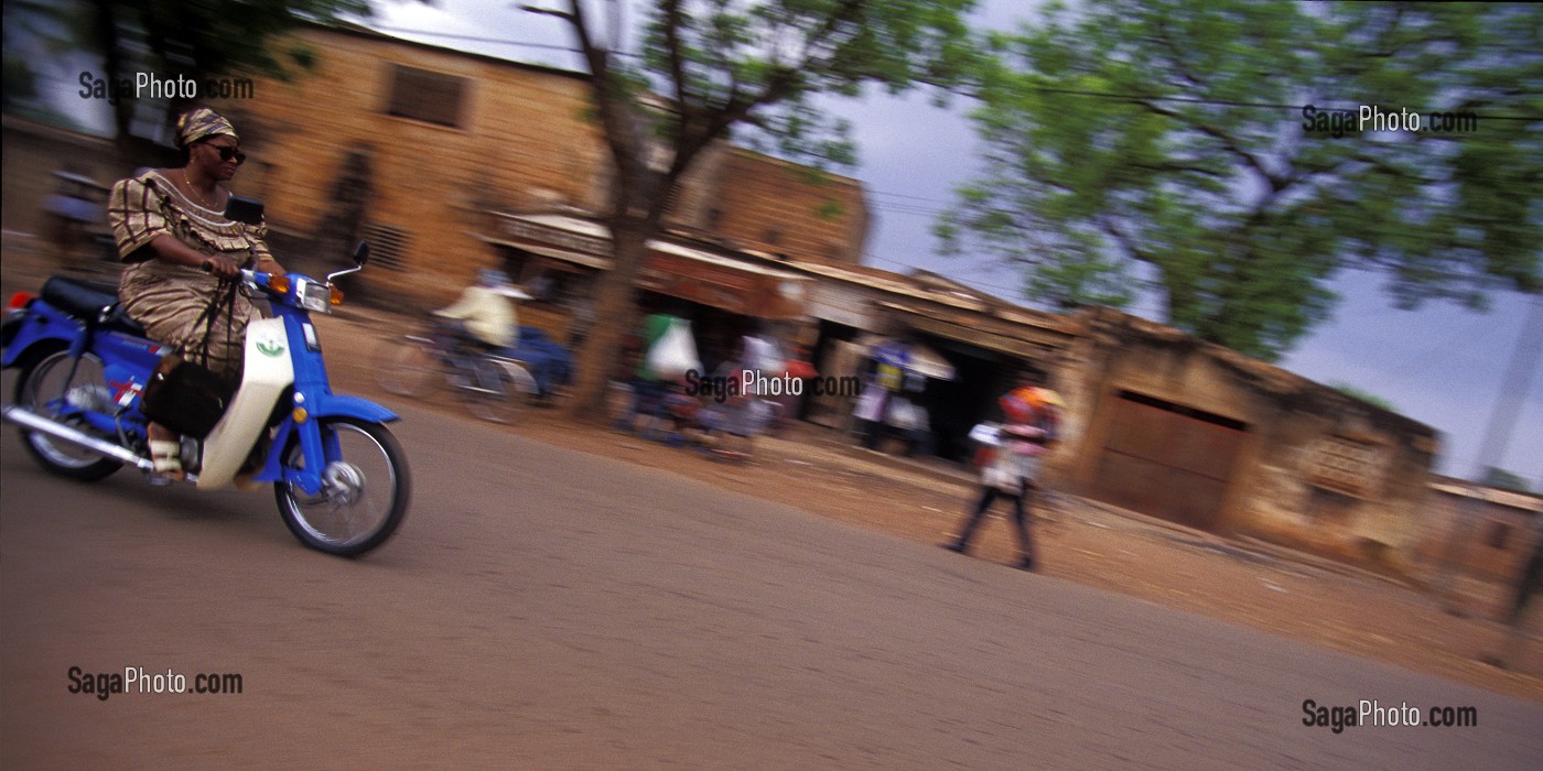 FEMME SE DEPLACANT A MOBYLETTE. MOYEN DE LOCOMOTION LE PLUS COURANT A BOBO-DIOULASSO, BURKINA FASO 
