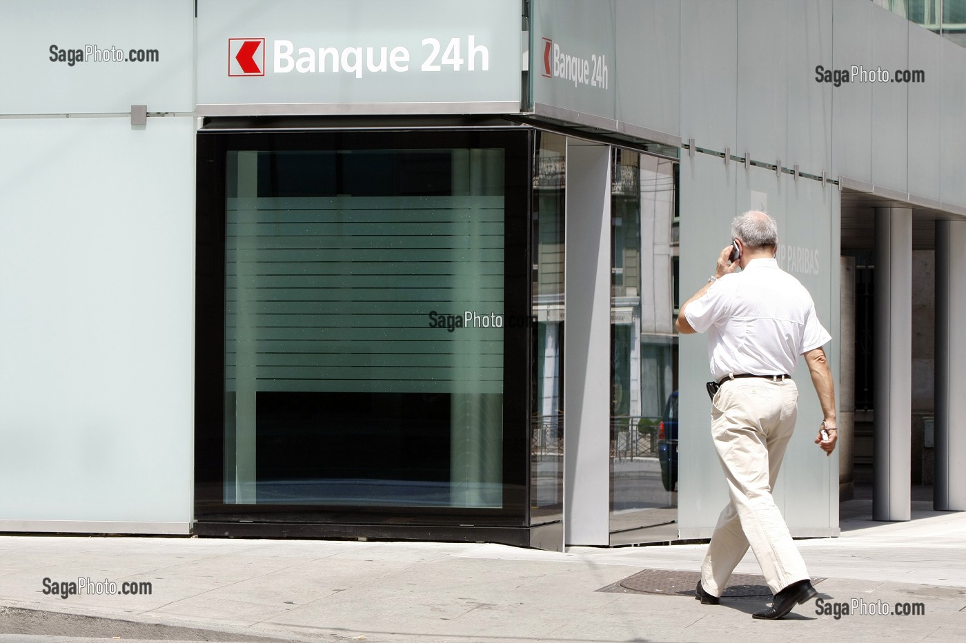 HOMME D'AFFAIRE AVEC SON TELEPHONE PORTABLE DEVANT UNE BANQUE 24H SUR 24, GENEVE, SUISSE 