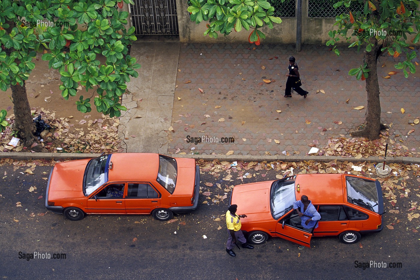 CHAUFFEUR DE TAXIS ET AGENT DE POLICE REGARDANT PASSER UNE JEUNE FEMME ABIDJAN, COTE D'IVOIRE 