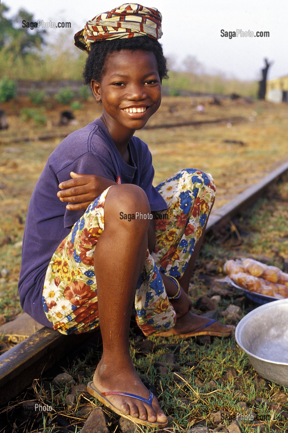 ENFANT ASSIS SUR UN RAIL, VENDANT DE LA NOURRITURE PRES DE LA GARE A LA FRONTIERE ENTRE LA COTE D'IVOIRE ET LE BURKINA FASO 