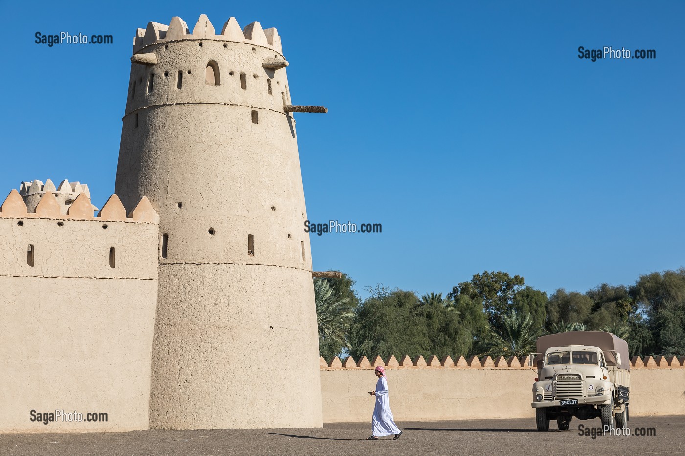 EMIRATI EN TENUE TRADITIONNELLE SE PROMENANT DANS L'ENCEINTE DU FORT D'AL JAHILI, VIEUX CAMION DE L'EPOQUE COLONIALE BRITANNIQUE, AL AIN, EMIRAT D'ABOU DABI, EMIRAT D'ABU DHABI, GOLFE PERSIQUE, EAU, EMIRATS ARABES UNIS 