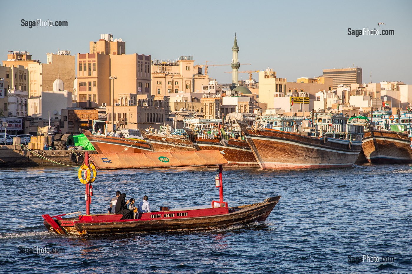 BARQUE A MOTEUR APPELE ABRA NAVIGANT DANS LA CRIQUE DE DUBAI AVEC DES BOUTRES ET LE QUARTIER DE DEIRA, MOSQUEE AVEC UN MINARET, DUBAI, GOLFE PERSIQUE, EAU, EMIRATS ARABES UNIS 