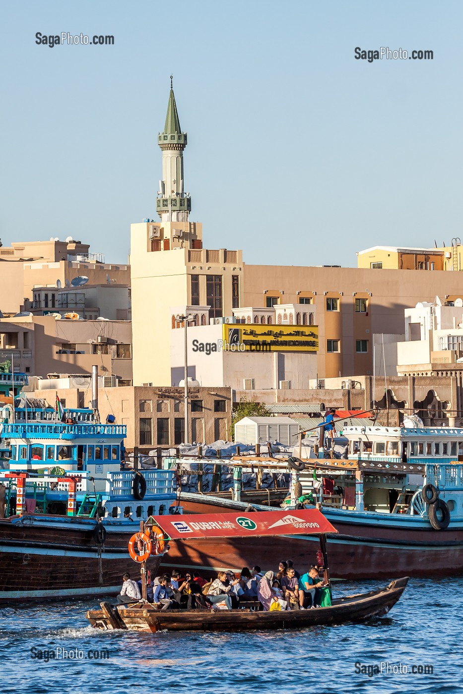BARQUE A MOTEUR APPELE ABRA NAVIGANT DANS LA CRIQUE DE DUBAI AVEC DES BOUTRES ET LE QUARTIER DE DEIRA, MOSQUEE AVEC UN MINARET, DUBAI, GOLFE PERSIQUE, EAU, EMIRATS ARABES UNIS 