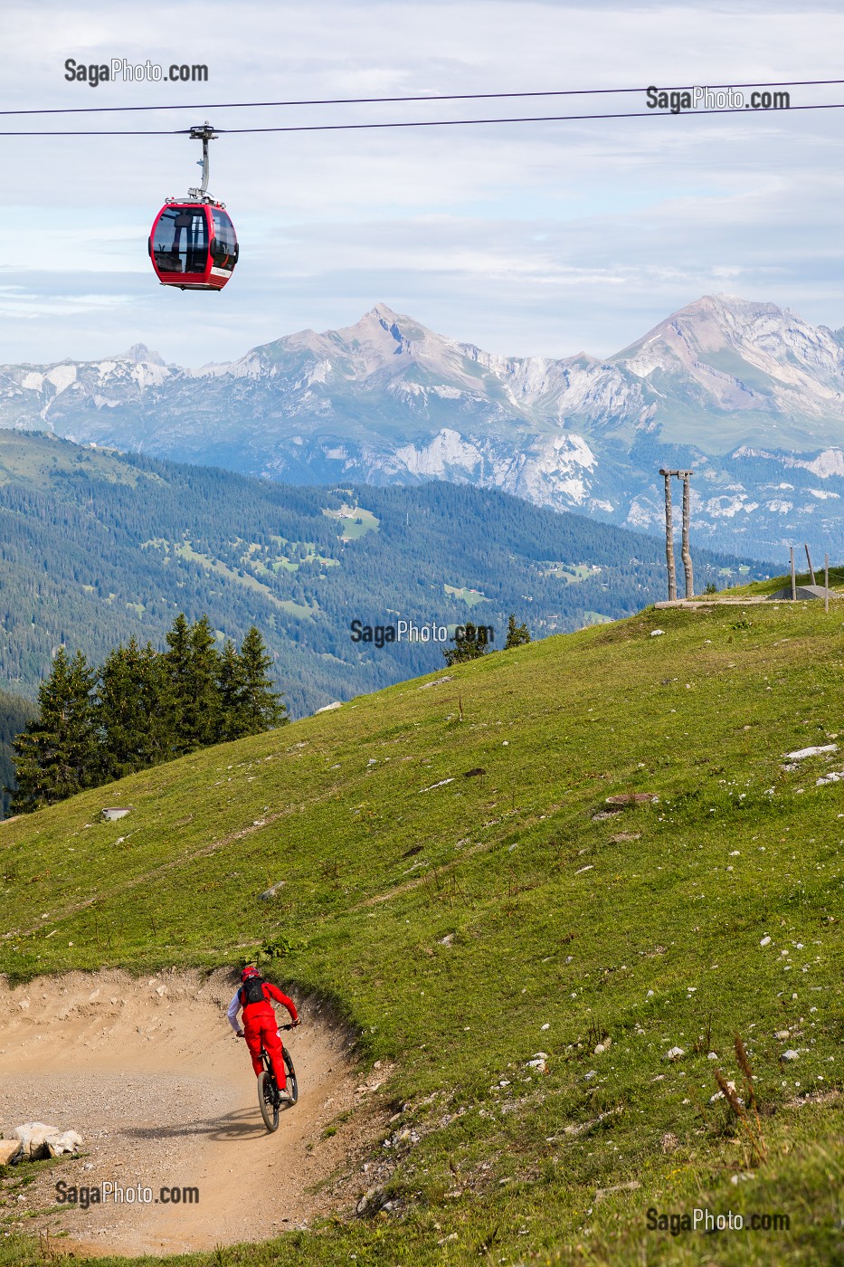 AMATEUR DE VTT DESCENDANT UNE PISTE DE VTT DANS LA STATION DE LENZERHEIDE AVEC LES TELECABINES ET LES ALPES SUISSES EN FOND, LENZERHEIDE, CANTON DES GRISONS, SUISSE 