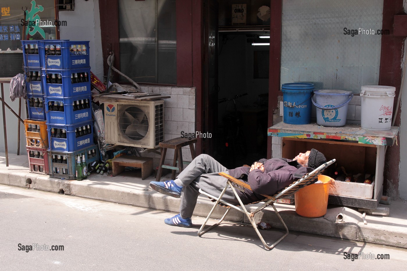 COMMERCANT FAISANT LA SIESTE DEVANT LA DEVANTURE DE SA BOUTIQUE DANS LA VIEILLE VILLE DE SHANGHAI, QUARTIER DE PUXI, SHANGHAI, REPUBLIQUE POPULAIRE DE CHINE 