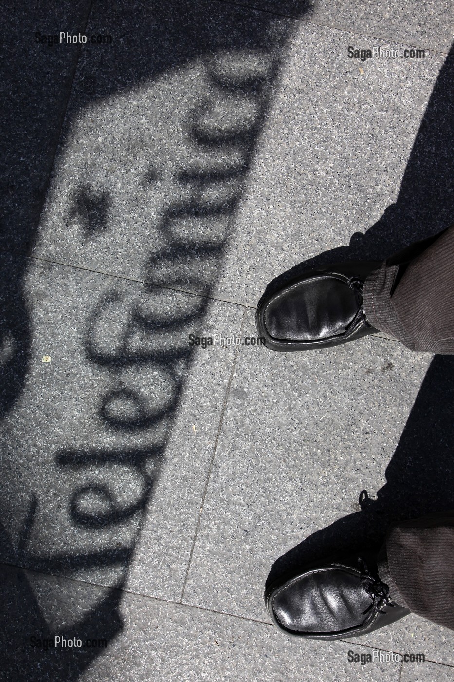 PIEDS ET CHAUSSURES DEVANT L'OMBRE D'UNE CABINE TELEPHONIQUE (TELEFONICA), QUARTIER LATINA, MADRID, ESPAGNE 