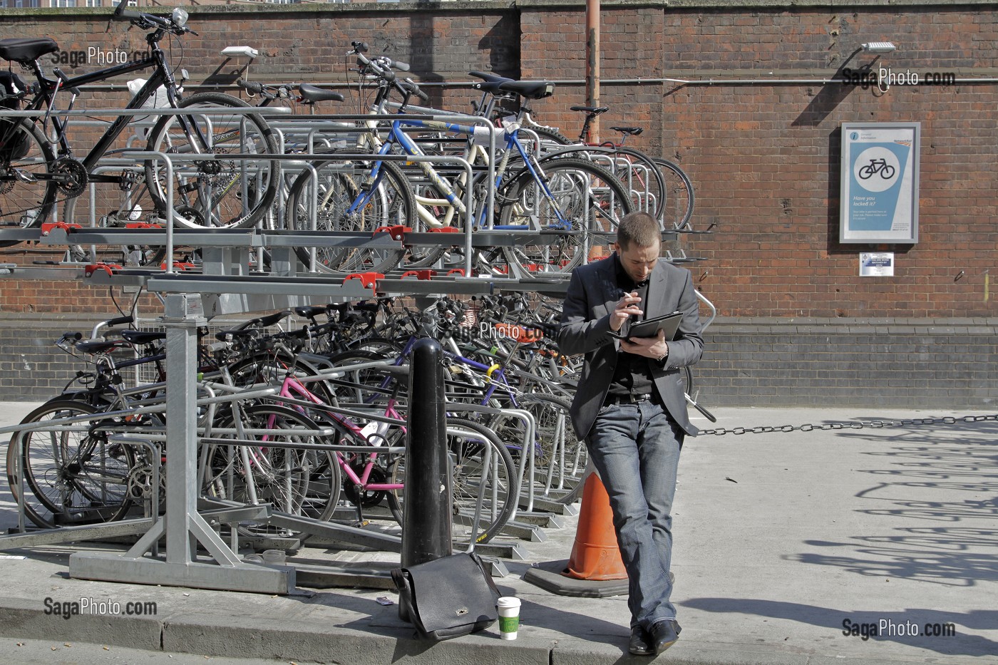 HOMME CONSULTANT SON IPAD AU PARKING A VELOS DE LA GARE DE WATERLOO, LONDRES, ANGLETERRE 