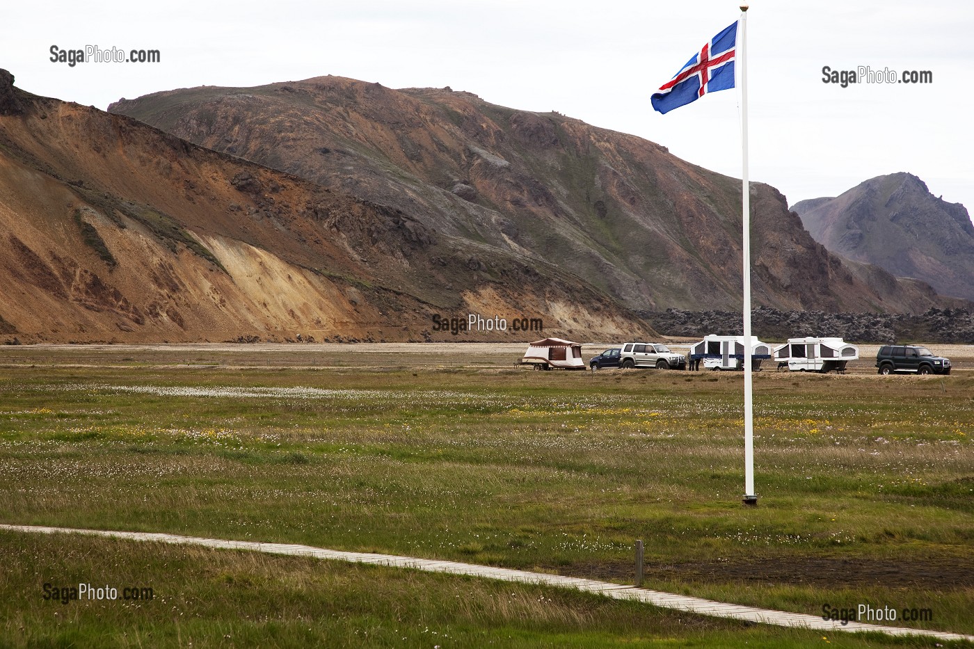 DRAPEAU ISLANDAIS FLOTTANT SUR LE CAMPING DE LANDMANNALAUGAR, AU CENTRE DE L'ISLANDE. PAYSAGE TOURMENTE OU L'ACTIVITE VOLCANIQUE A FORME DES CRATERES ROUGEATRES ET DES MONTAGNES DE RHYOLITE, HAUTES TERRES D’ISLANDE, EUROPE 