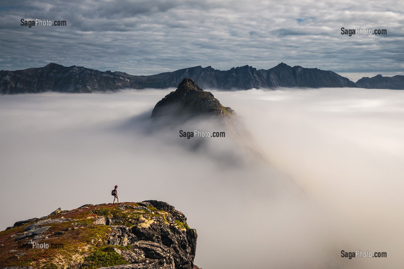 RANDONNEUSE AU SOMMET DU MONT HESTEN CONTEMPLANT DES PICS EMERGEANT D'UNE MER DE NUAGES, FJORDGARD, SENJA, NORVEGE 