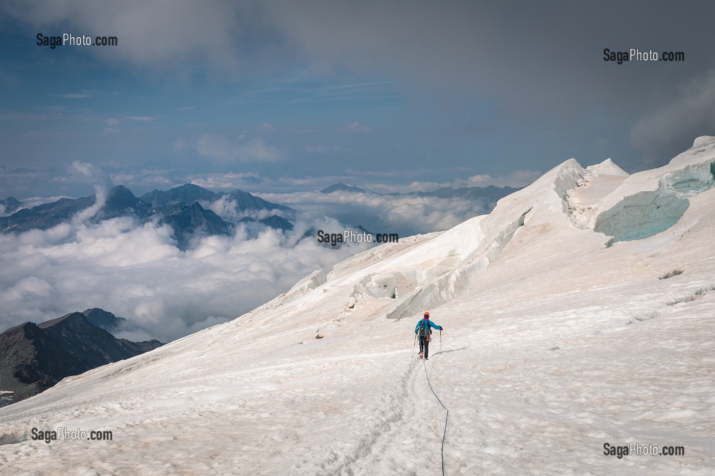 ALPINISTE TRAVERSANT UN GLACIER CREVASSE AU DESSUS D'UNE MER DE NUAGES, MASSIF DU MONT-ROSE, GRESSONEY-LA-TRINITE, VAL D'AOSTE, ITALIE 