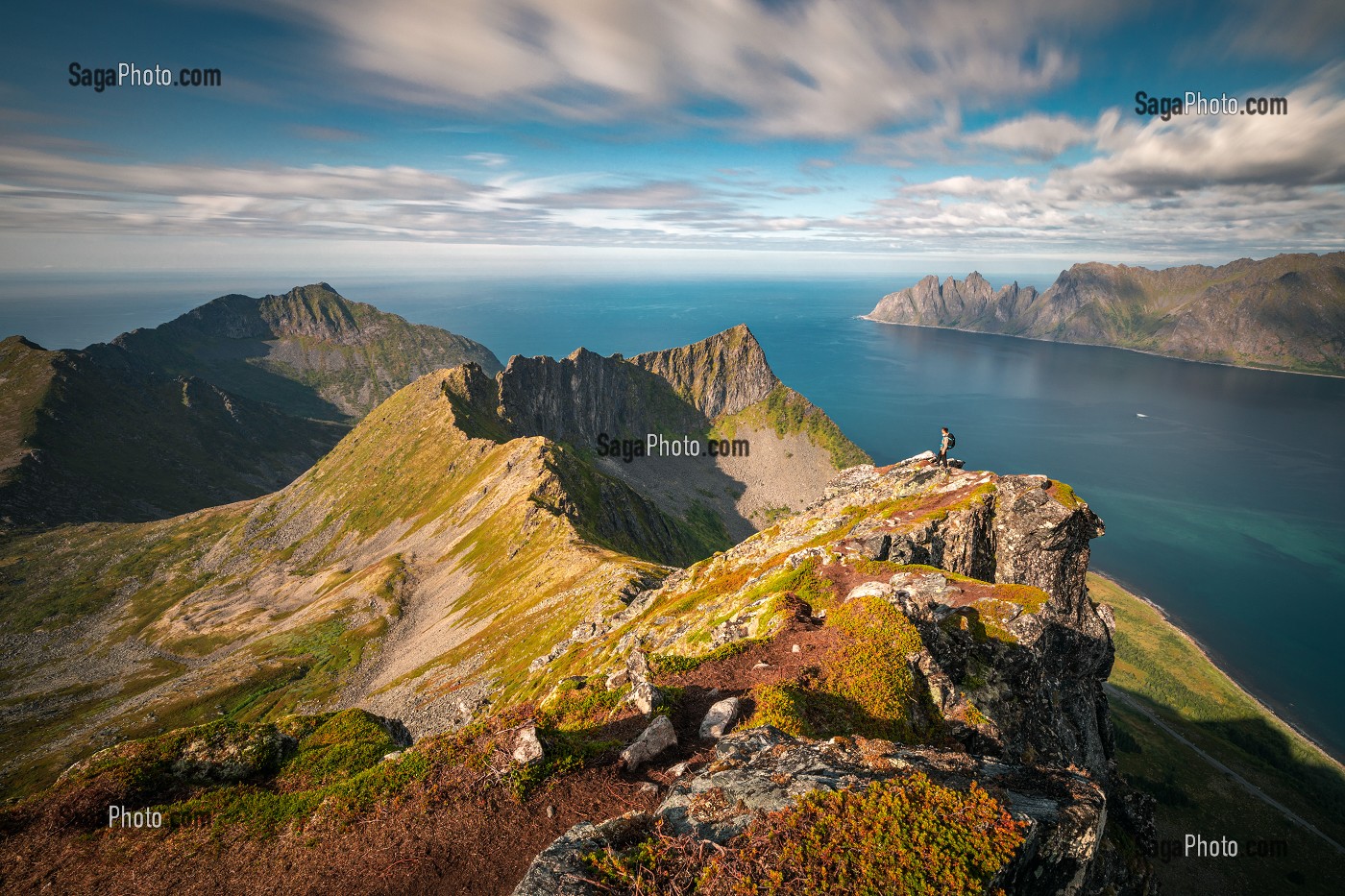 RANDONNEUR AU COUCHER DU SOLEIL AU SOMMET DU MONT HUSFJELLET, FJORDS ET MONTAGNES EN ARRIERE-PLAN, SENJA, NORVEGE 