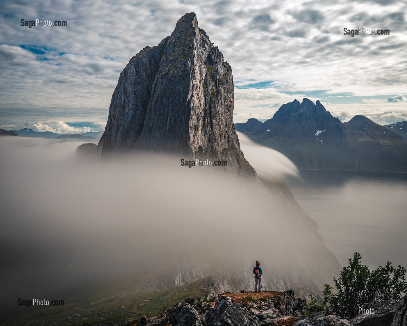 RANDONNEUSE AU PIED DU MONT SEGLA ENTOURE DE NUAGES SE JETANT DANS LE FJORD, FJORDGARD, SENJA, NORVEGE 