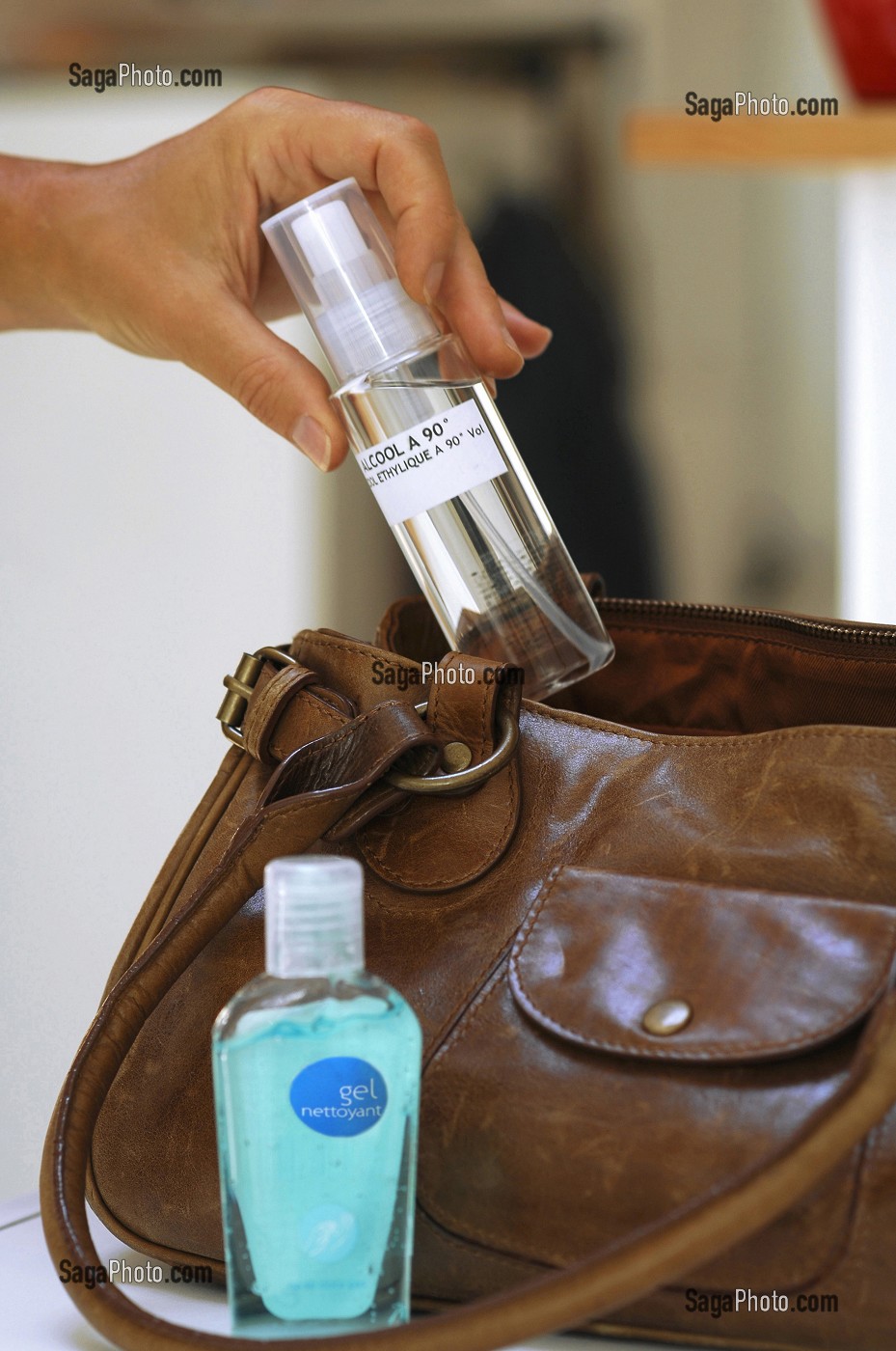 FEMME RANGEANT DES FLACONS DE LOTION DESINFECTANTE ET D'ALCOOL A 90 DEGRES DANS SON SAC A MAIN, GESTES DE PREVENTION ET DE LUTTE CONTRE LE VIRUS H1N1 OU LA GRIPPE A 