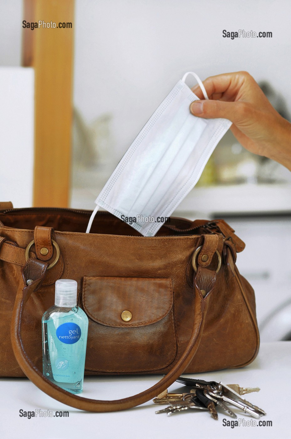 FEMME RANGEANT UN FLACON DE LOTION DESINFECTANTE ET UN MASQUE CHIRURGICAL DANS SON SAC A MAIN, GESTES DE PREVENTION ET DE LUTTE CONTRE LE VIRUS H1N1 OU LA GRIPPE A 