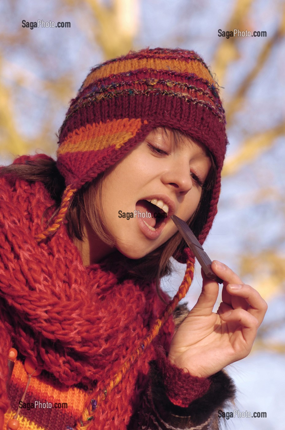 FROID ET CALORIES. JEUNE FEMME MANGEANT DU CHOCOLAT LORS D'UNE PROMENADE EN FORET 