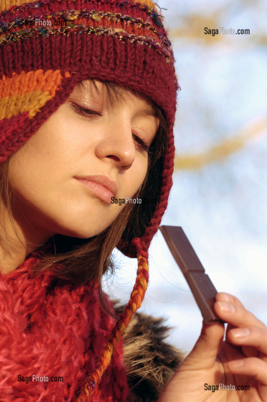 FROID ET CALORIES. JEUNE FEMME MANGEANT DU CHOCOLAT LORS D'UNE PROMENADE EN FORET 
