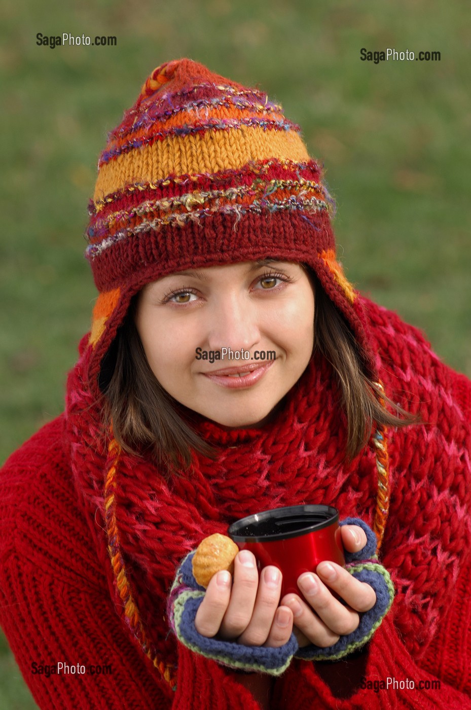 FROID ET CALORIES. JEUNE FEMME SE RECHAUFFANT ET SE RESTAURANT AVEC UNE BOISSON CHAUDE ET UN PETIT GATEAU, LORS D'UNE PROMENADE DANS LA NATURE 