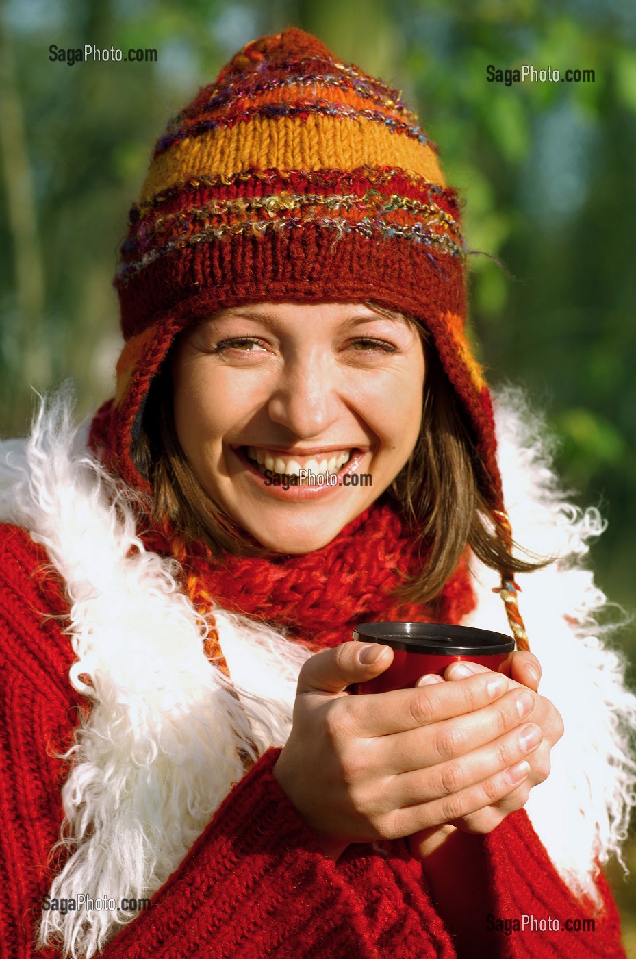 JEUNE FEMME SE RECHAUFFANT AVEC UNE BOISSON CHAUDE, LORS D'UNE PROMENADE EN FORET 
