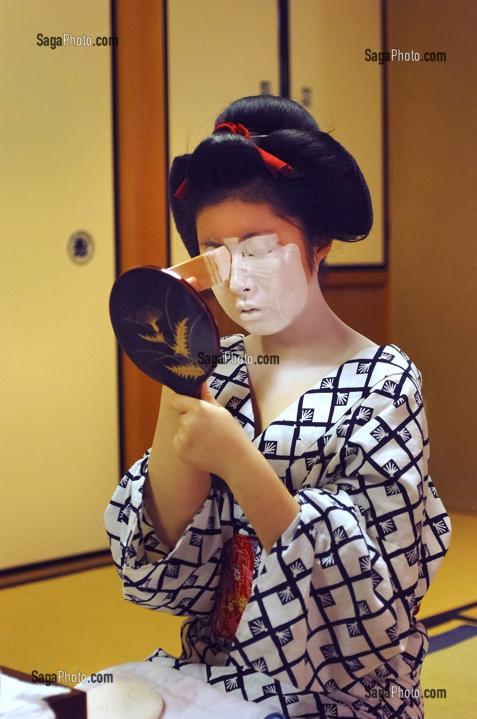 MAQUILLAGE TRADITIONNEL (DORAN) D’UNE MAIKO (APPRENTIE GEISHA), APPLICATION DU FARD BLANC (SHIRONURI) SUR LE VISAGE AVEC UN PINCEAU DE BAMBOU (BURASHI), LA COIFFURE DE LA MAIKO EST UN CHIGNON EN FORME DE PECHE FENDUE (WARESHINOBU) ORNE DE RUBANS EN SOIE (KANOKO), QUARTIER DE GION, KYOTO, JAPON, ASIE 