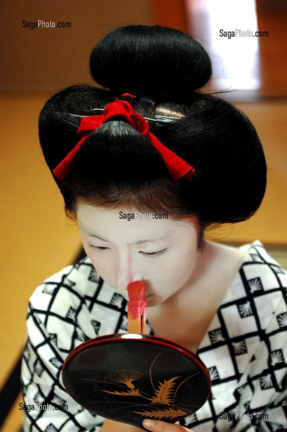 MAQUILLAGE TRADITIONNEL (DORAN) D’UNE MAIKO (APPRENTIE GEISHA), APPLICATION SUR LE VISAGE DU FARD ROSE POUR MODELER LES TRAITS AVEC UN PINCEAU DE BAMBOU (BURASHI), LA COIFFURE DE LA MAIKO EST UN CHIGNON EN FORME DE PECHE FENDUE (WARESHINOBU) ORNE DE RUBANS EN SOIE (KANOKO), QUARTIER DE GION, KYOTO, JAPON, ASIE 