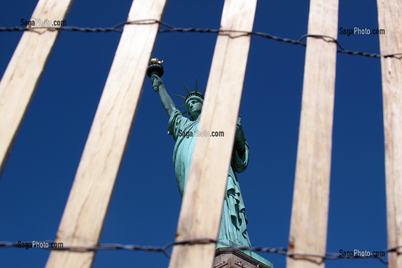 STATUE DE LA LIBERTE VUE A TRAVERS UNE PALISSADE EN BOIS ET EN FIL DE FER, LIBERTY ISLAND, PORT DE NEW YORK CITY, ETAT DE NEW YORK, ETATS-UNIS 
