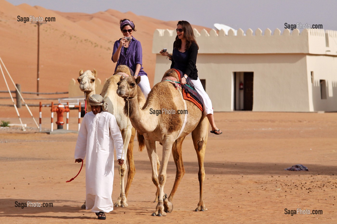 TOURISTES CANADIENNES FAISANT UN TOUR A DOS DE DROMADAIRES DANS L'ENCEINTE DU COMPLEXE TOURISTIQUE DESERT NIGHT CAMP, DESERT DE WAHIBA SANDS, SULTANAT D'OMAN, MOYEN-ORIENT 