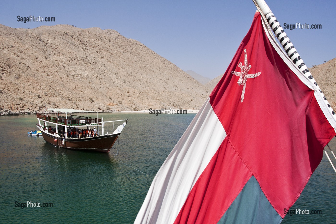 DRAPEAU NATIONAL OMANAIS ET BOUTRE TRADITIONNEL MOUILLANT DANS LES EAUX DE LA PENINSULE DE MUSANDAM, SULTANAT D'OMAN, MOYEN-ORIENT 