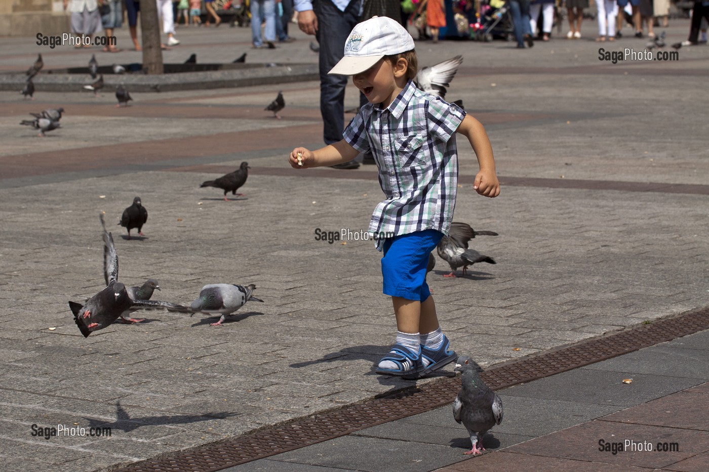 PETIT GARCON JOUANT A CHASSER LES PIGEONS SUR LA PLACE DU MARCHE (RYNEK GLOWNY), VIEILLE VILLE DE CRACOVIE, POLOGNE 