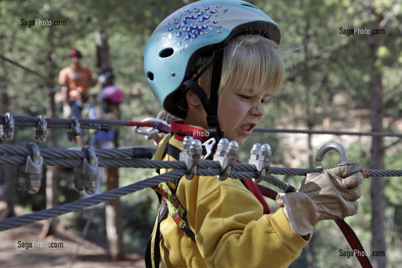 ACCROCHAGE D'UN MOUSQUETON SUR LE CABLE POUR LA MISE EN SECURITE, ENFANT SUR LE PARCOURS ACROBATIQUE, ACCRO-PARK (PARC ACCROBRANCHE DANS LES ARBRES), DOMAINE DE TERRES D’AMANAR, TAHANAOUTE, AL HAOUZ, MAROC 