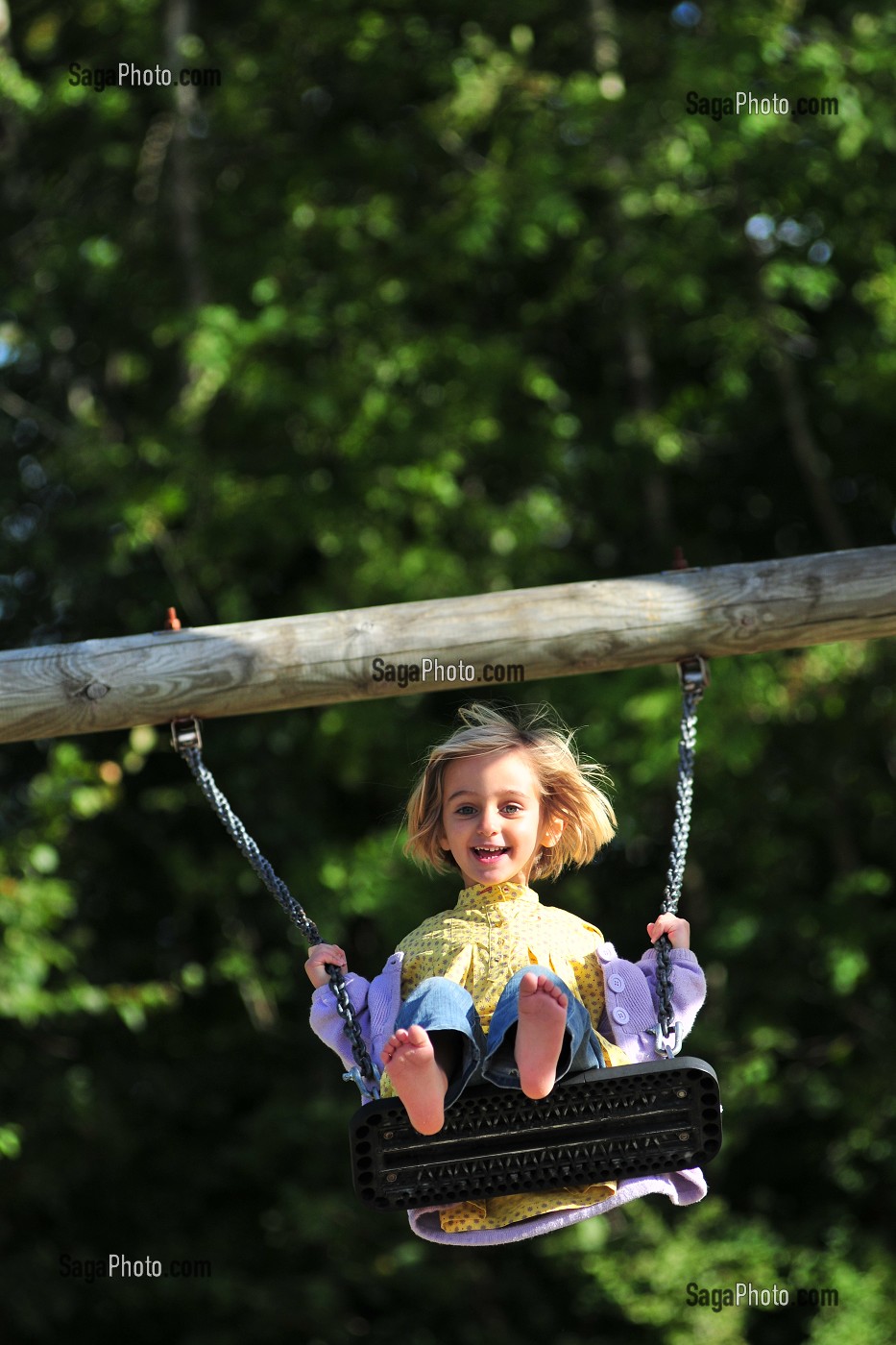 PETITE FILLE JOUANT A LA BALANCOIRE DANS UN JARDIN 