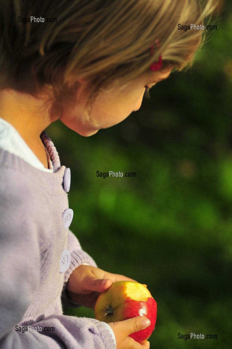 PETITE FILLE MANGEANT UNE POMME DANS SON JARDIN 