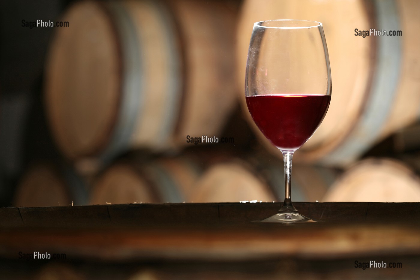 VERRE DE VIN ROUGE DANS UN ENVIRONEMENT DE CAVE ET BARRIQUES 