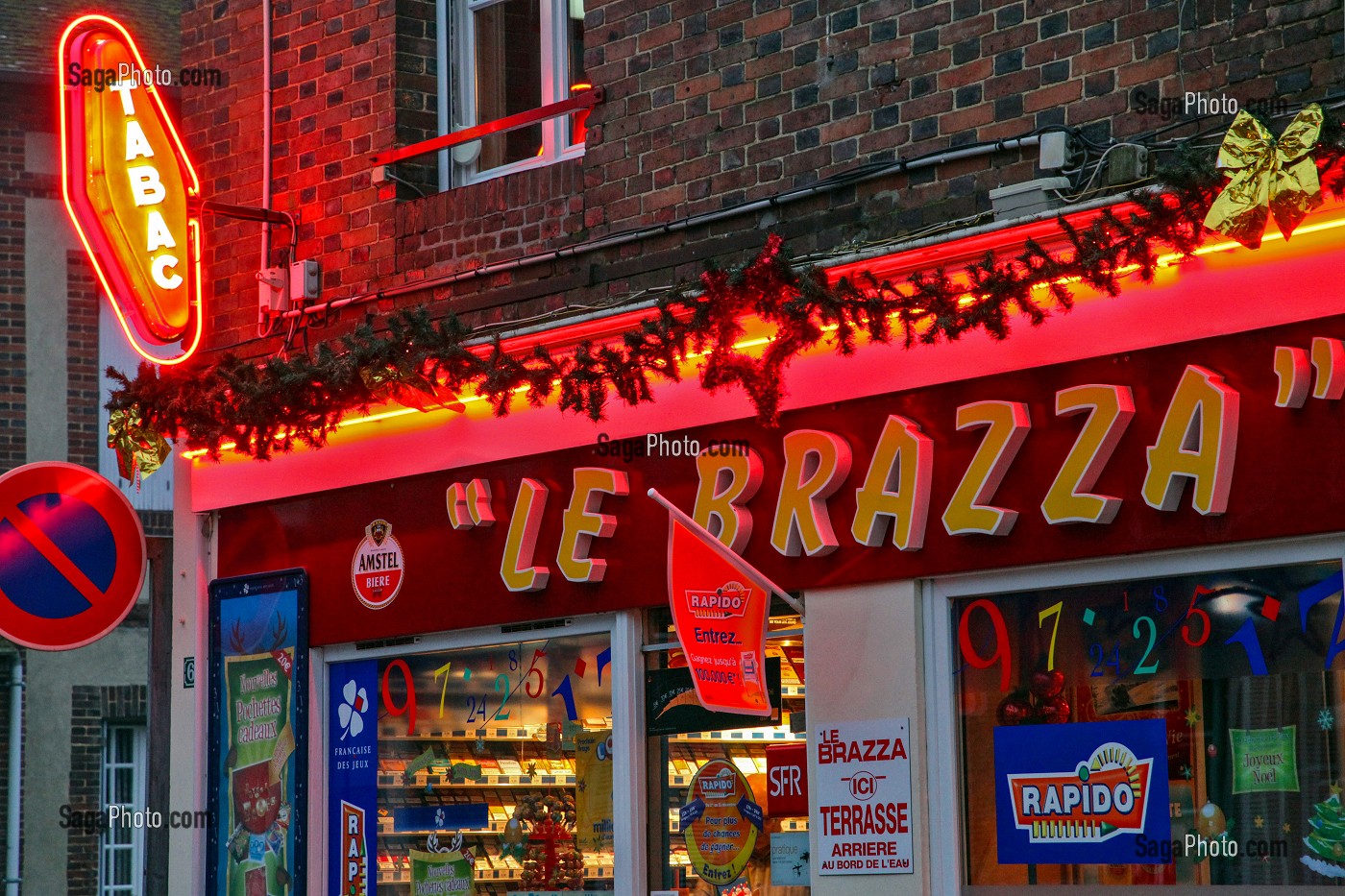 ENSEIGNE D'UN BAR TABAC 'LE BRAZZA' A LA TOMBEE DE LA NUIT AVEC VITRINE POUR LA PROMOTION DES JEUX DE HASARD (TICKETS A GRATTER, RAPIDO, FRANCAISE DES JEUX), FRANCE 