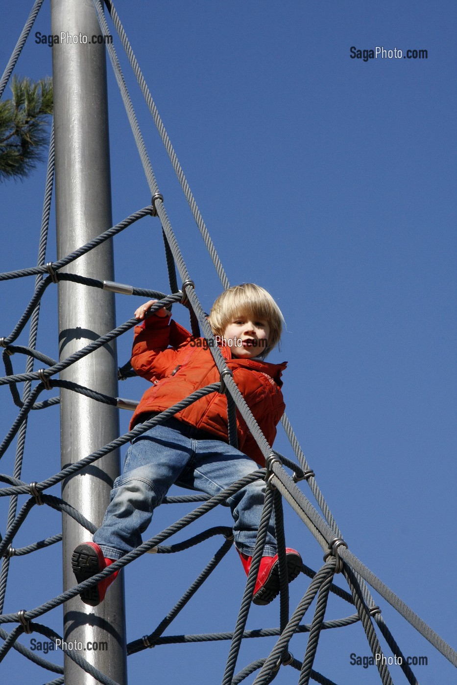 ESCALADE DES CORDES DE LA TOILE D'ARAIGNEE (STRUCTURE GRIMPANTE) PAR UN PETIT GARCON, AIRE DE JEUX POUR ENFANTS, JARDIN D'ACCLIMATATION, PARIS, FRANCE 