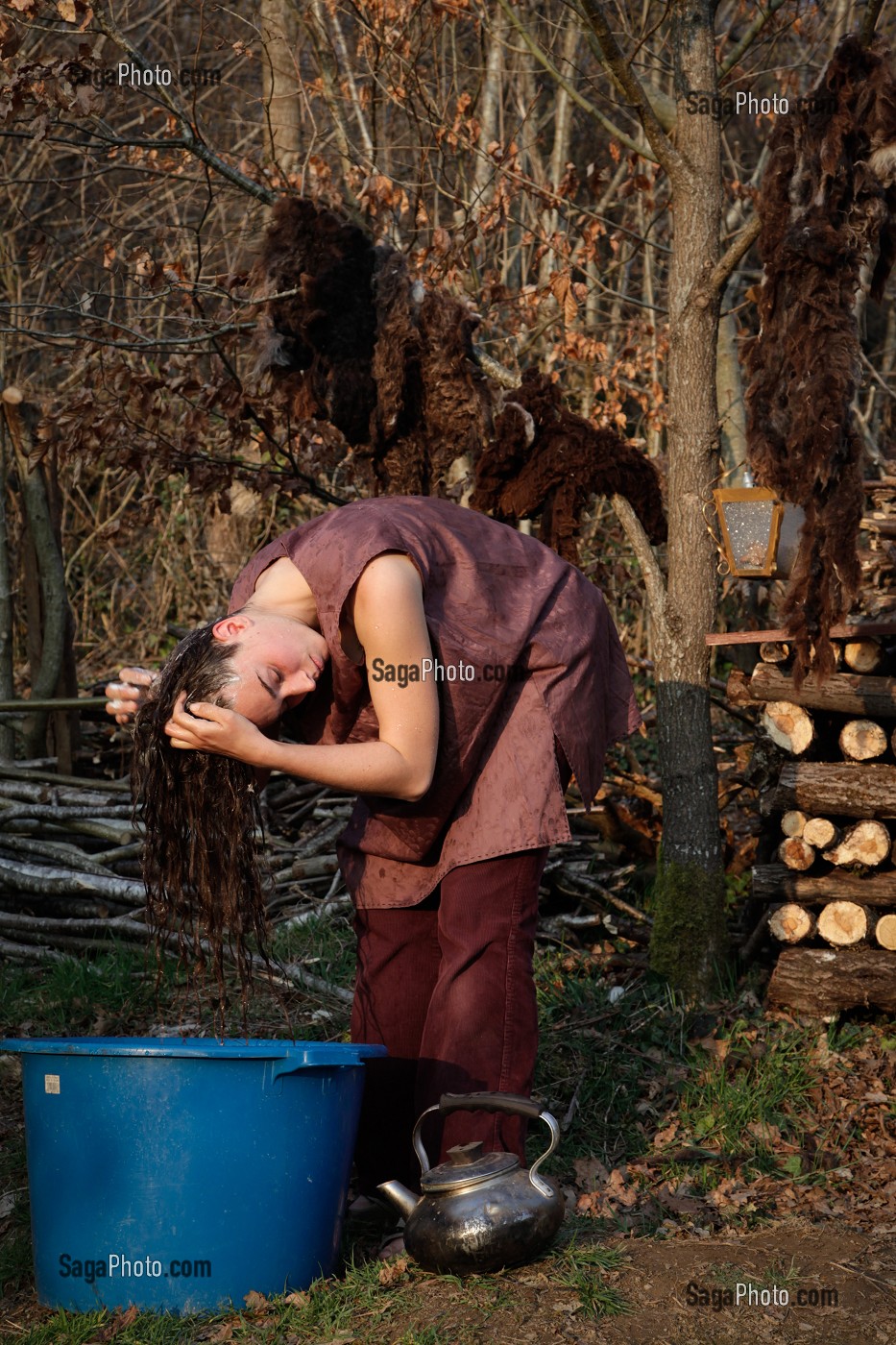 LORELEI SE LAVE LES CHEVEUX APRES AVOIR FAIT CHAUFFER L'EAU DANS LA BOUILLOIRE, ELLE A TOUT QUITTE POUR CONSTRUIRE ET HABITER SA CABANE EN BOIS AU MILIEU DE LA CREUSE, FRANCE 