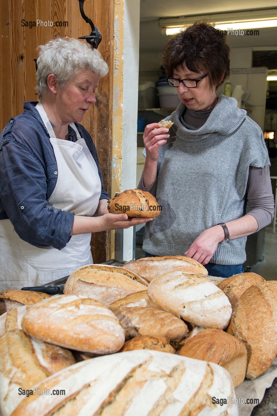 BLANDINE ZOUTARD FAISANT GOUTER SON PAIN BIO A NATHALIE DE WEVER, COMMERCANTE ET ADHERENTE DU MOUVEMENT LOCAVORE, DANS SA BOULANGERIE DE PAIN BIO, FERME DE SAINT-MAMERT, BUIS-SOUS-DANVILLE, EURE (27), FRANCE 