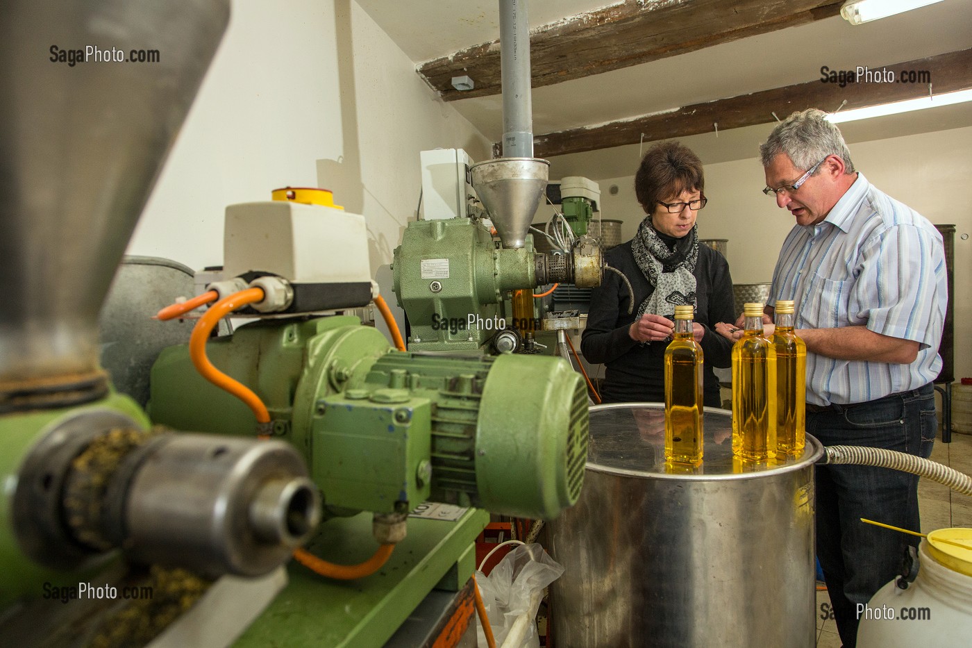 JEAN-MARIE LENFANT, PRODUCTEUR D'HUILE DE COLZA ET DE TOURNESOL, FAISANT GOUTER SA PRODUCTION A NATHALIE DE WEVER, COMMERCANTE ADHERENTE DU MOUVEMENT LOCAVORE, DEVANT DES BOUTEILLES D'HUILE DE COLZA, LA COUTURE-BOUSSEY, EURE (27), FRANCE 