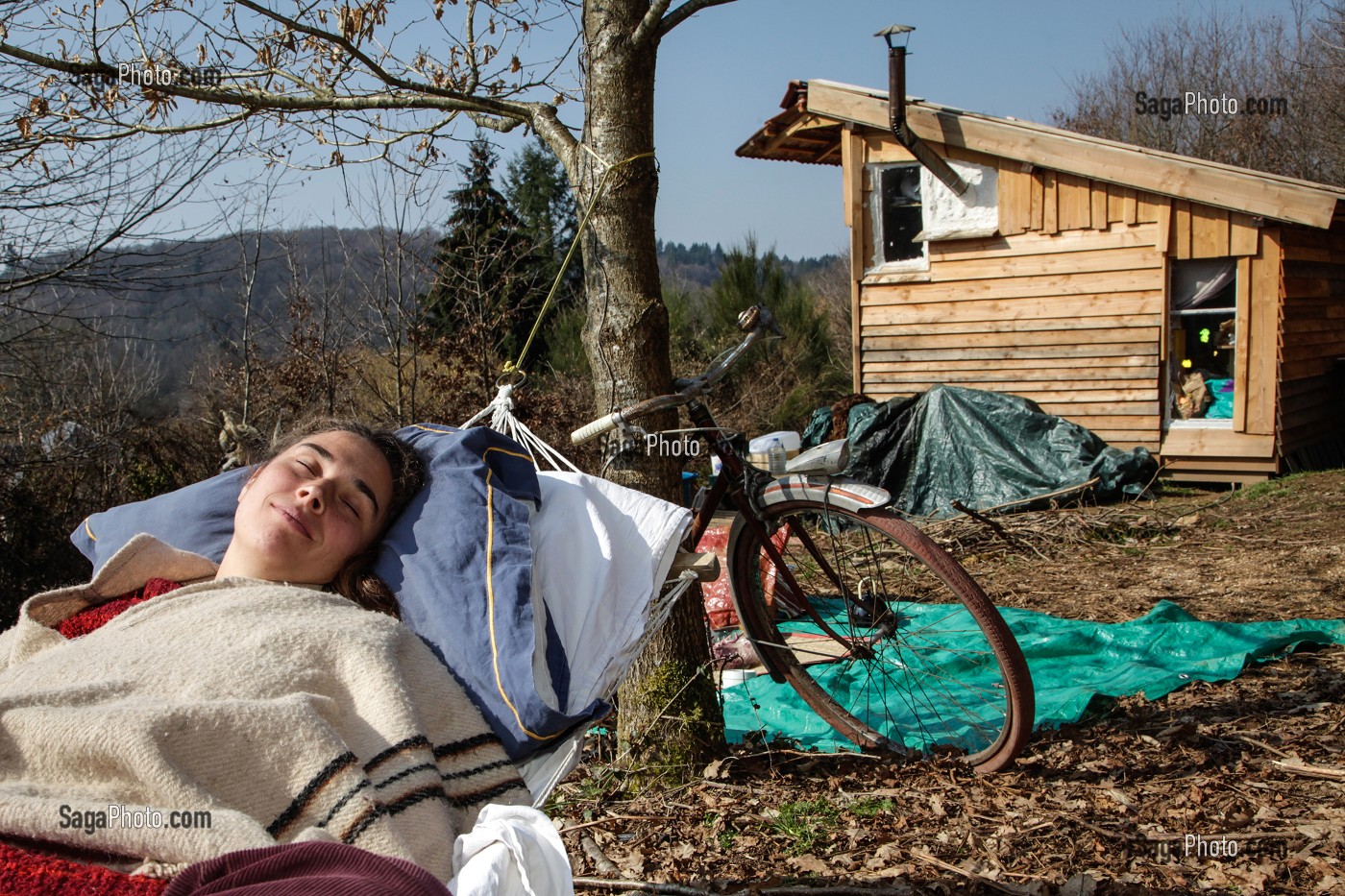 LORELEI FAIT LA SIESTE DANS SON HAMAC, ELLE A TOUT QUITTE POUR CONSTRUIRE ET HABITER SA CABANE EN BOIS AU MILIEU DE LA CREUSE, FRANCE 