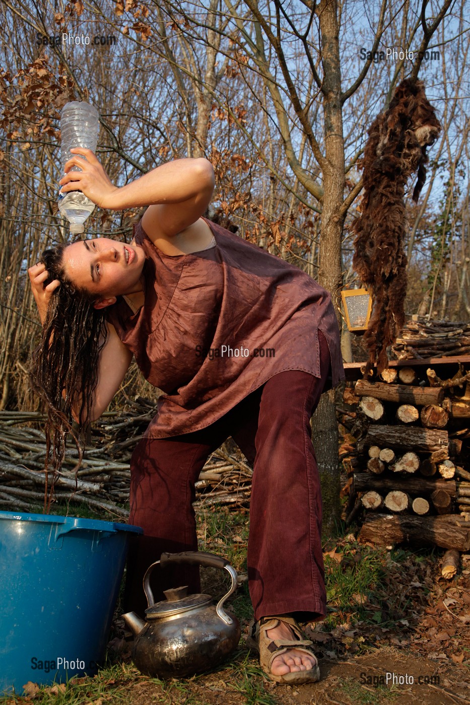 LORELEI SE LAVE LES CHEVEUX APRES AVOIR FAIT CHAUFFER L'EAU DANS LA BOUILLOIRE, ELLE A TOUT QUITTE POUR CONSTRUIRE ET HABITER SA CABANE EN BOIS AU MILIEU DE LA CREUSE, FRANCE 