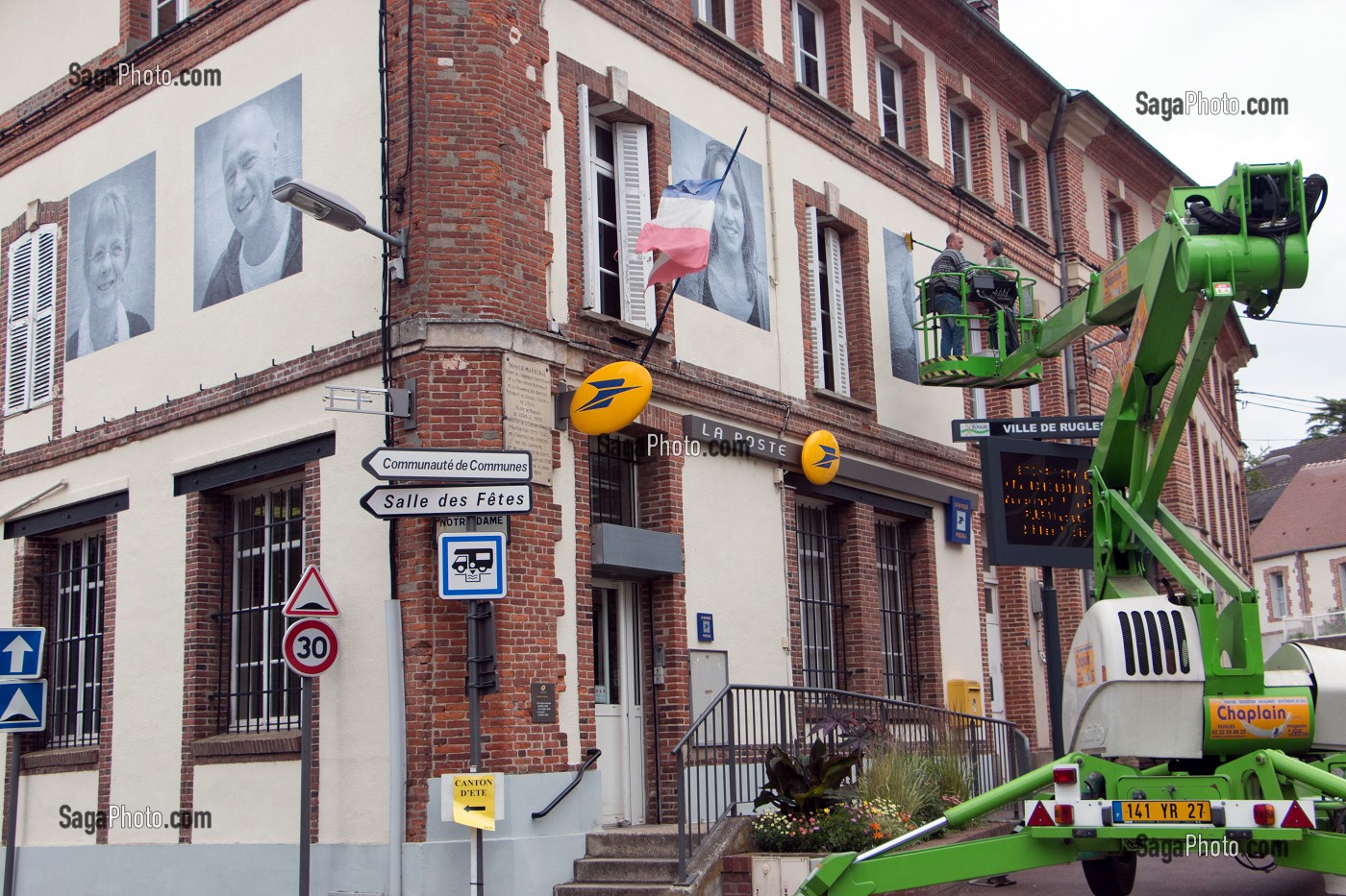 COLLAGE AVEC UNE NACELLE DES PHOTOS GEANTES SUR LES MURS (LA POSTE) DE LA VILLE POUR LE FESTIVAL CULTUREL RUGL'ART, RUGLES, (27) EURE, FRANCE 