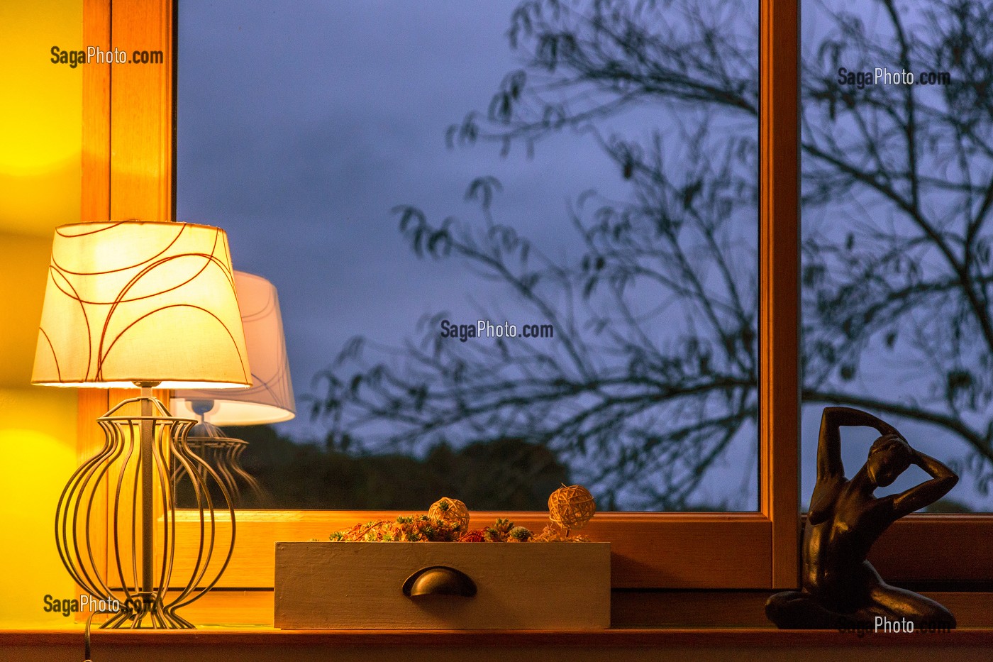 ECLAIRAGE INTERIEUR D'UNE MAISON A LA TOMBEE DE LA NUIT AVEC VUE SUR LE JARDIN 
