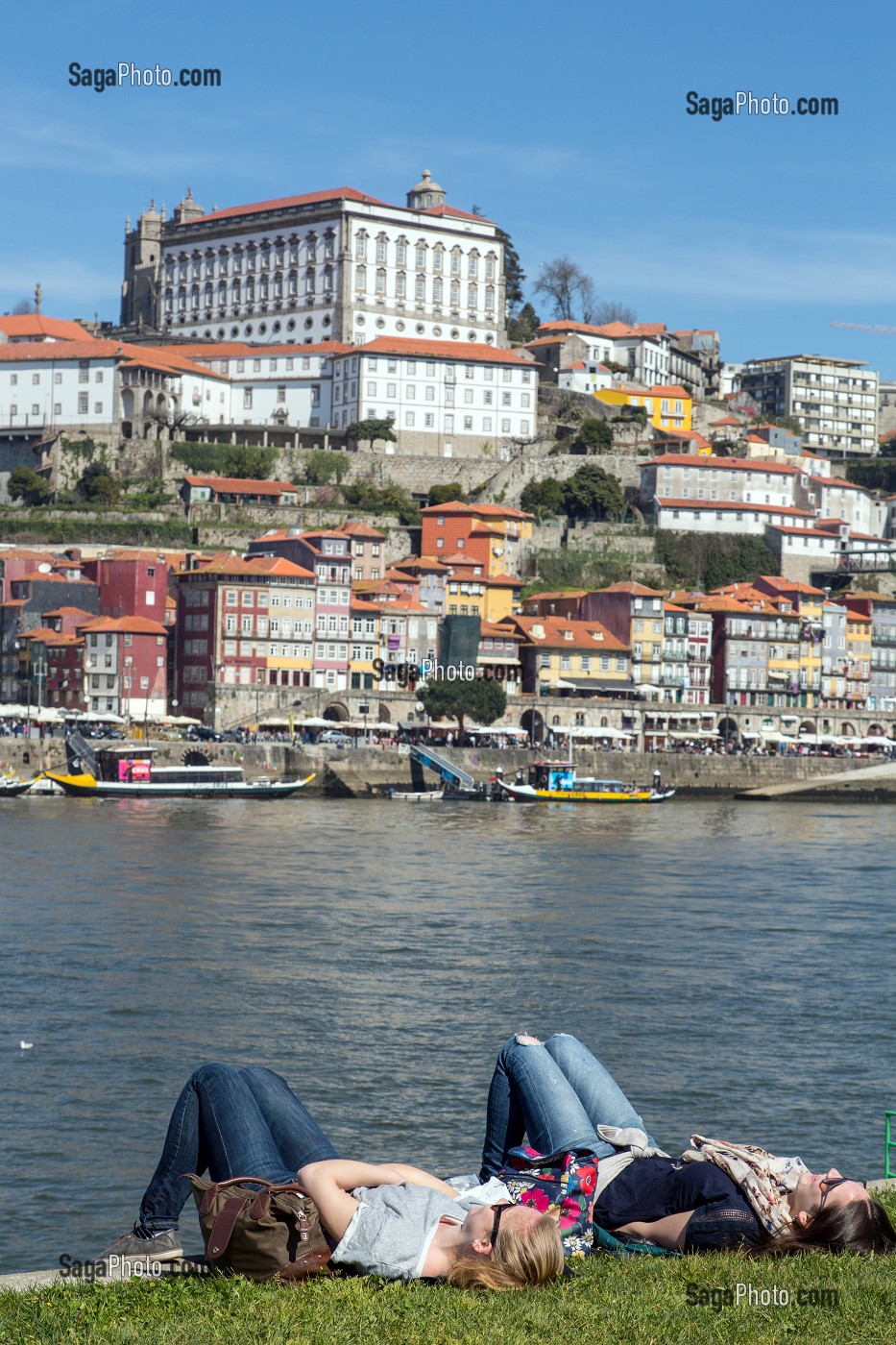 TOURISTES ALLONGES SUR LES BERGES DU DOURO FACE A LA VILLE DE PORTO, VILA NOVA DE GAIA, PORTUGAL 