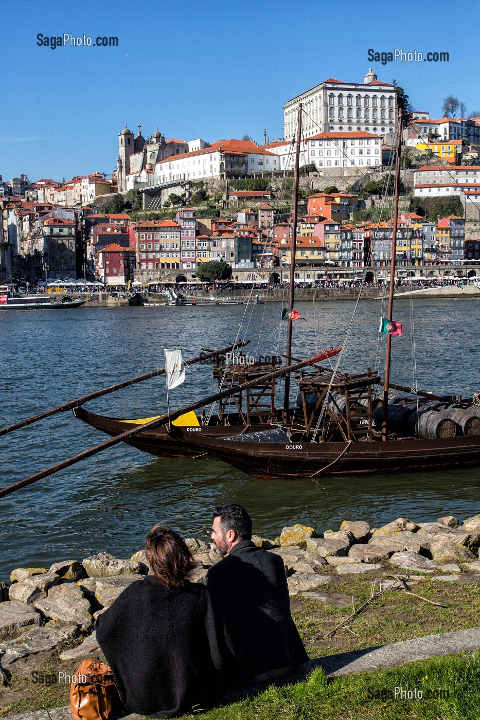 PROMENEURS AU BORD DU DOURO DEVANT LES BATEAUX A FOND PLAT POUR LE TRANSPORT DU VIN (BARCOS RABELOS) AVEC LA VILLE ET LE PALAIS EPISCOPAL VILA NOVA DE GAIA, PORTO, PORTUGAL 