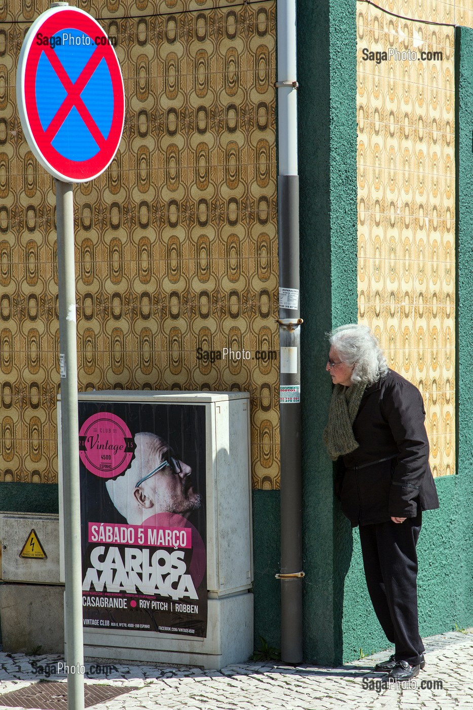 SCENE DE RUE, UNE FEMME SURVEILLE LES PASSAGES SOUS LE REGARD D'UNE AFFICHE DE CARLOS MANACA, VILLE BALNEAIRE D'ESPINHO, PORTUGAL 